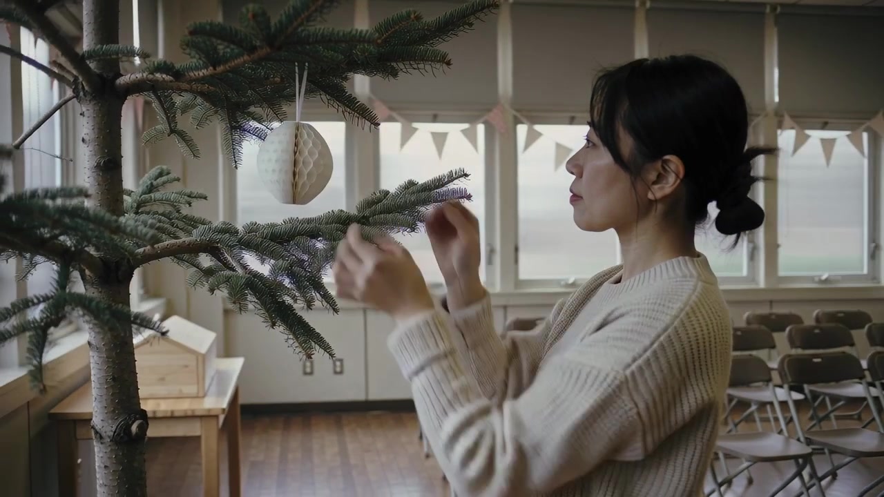 Placing woman in sweater bun hanging ornament on tree preparing meeting room, copy space