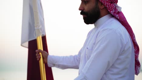 Un-Caballero-Montando-Un-Caballo-Sosteniendo-La-Bandera-De-Qatar-Cerca-Del-Mar-2