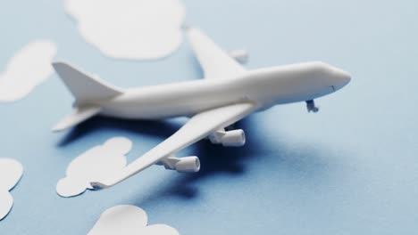 close up of white airplane model with white clouds and copy space on blue background