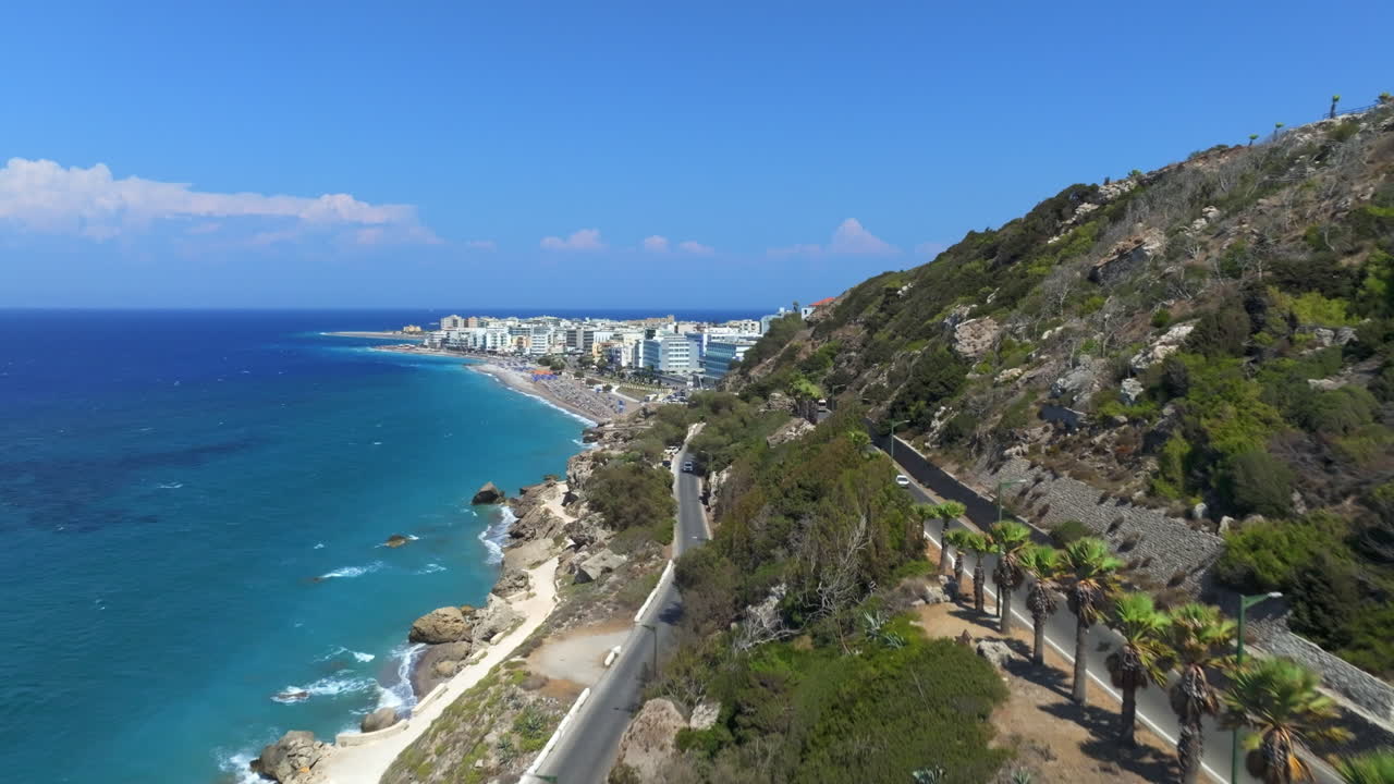 Drone following cars on a seaside road, approaching Rhodes city, in sunny Greece