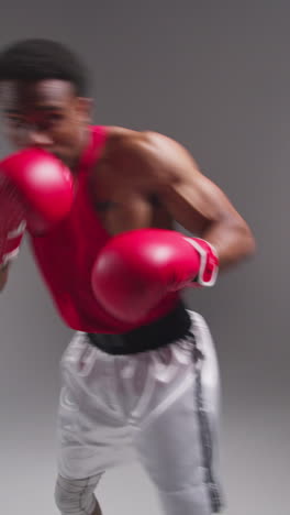 Vídeo-Vertical-En-Tiempo-Real,-Toma-De-Estudio-En-Primera-Persona-De-Un-Boxeador-Con-Guantes-De-Boxeo-En-Una-Pelea-De-Boxeo,-Golpeando-Hacia-La-Cámara-1