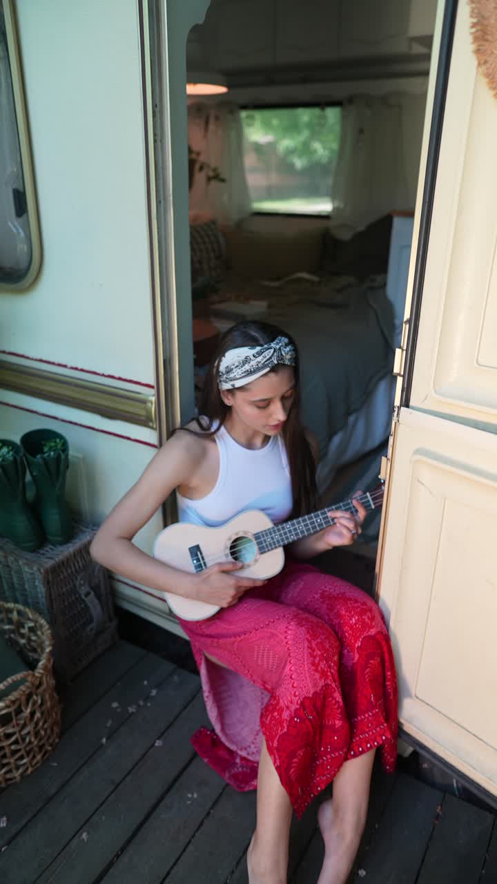 mujer tocando el ukulele en un porche de campervan