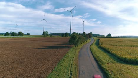 Car-passing-a-corn-field-near-wind-turbines-aerial