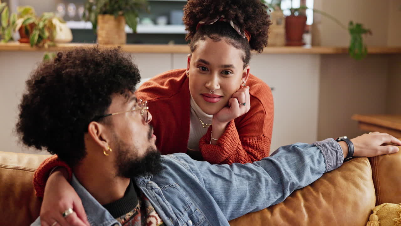 A loving couple sitting on a couch together, looking at each other with smiles
