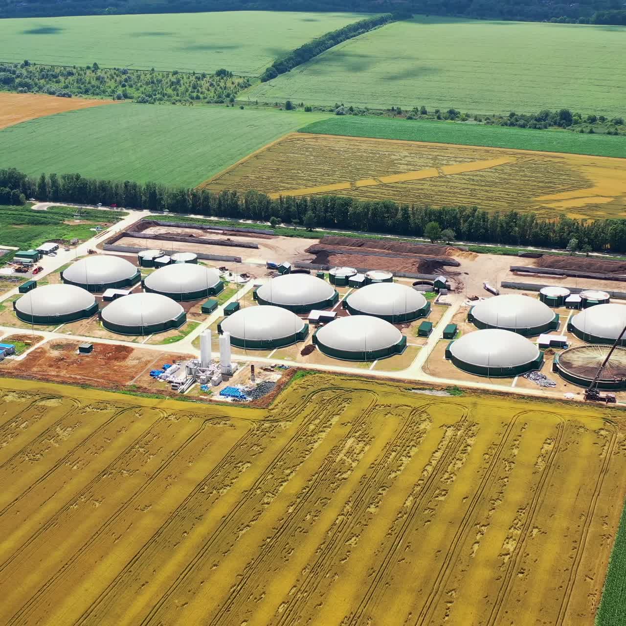 Storage tanks for biomass on fields background. Agricultural and greenhouse complex is equipped with its own biogas. Aerial view