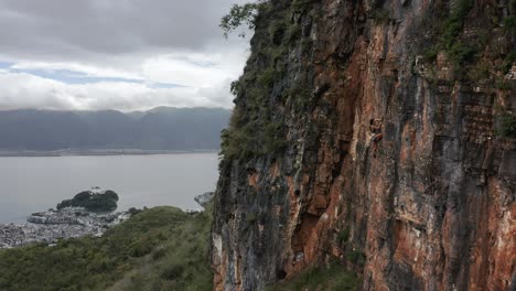 female rock climber ascending rock face precipice, aerial view