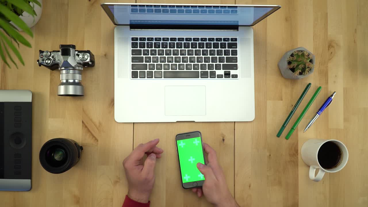 colocación plana de las manos del hombre usando el teléfono con pantalla verde en el lugar de trabajo