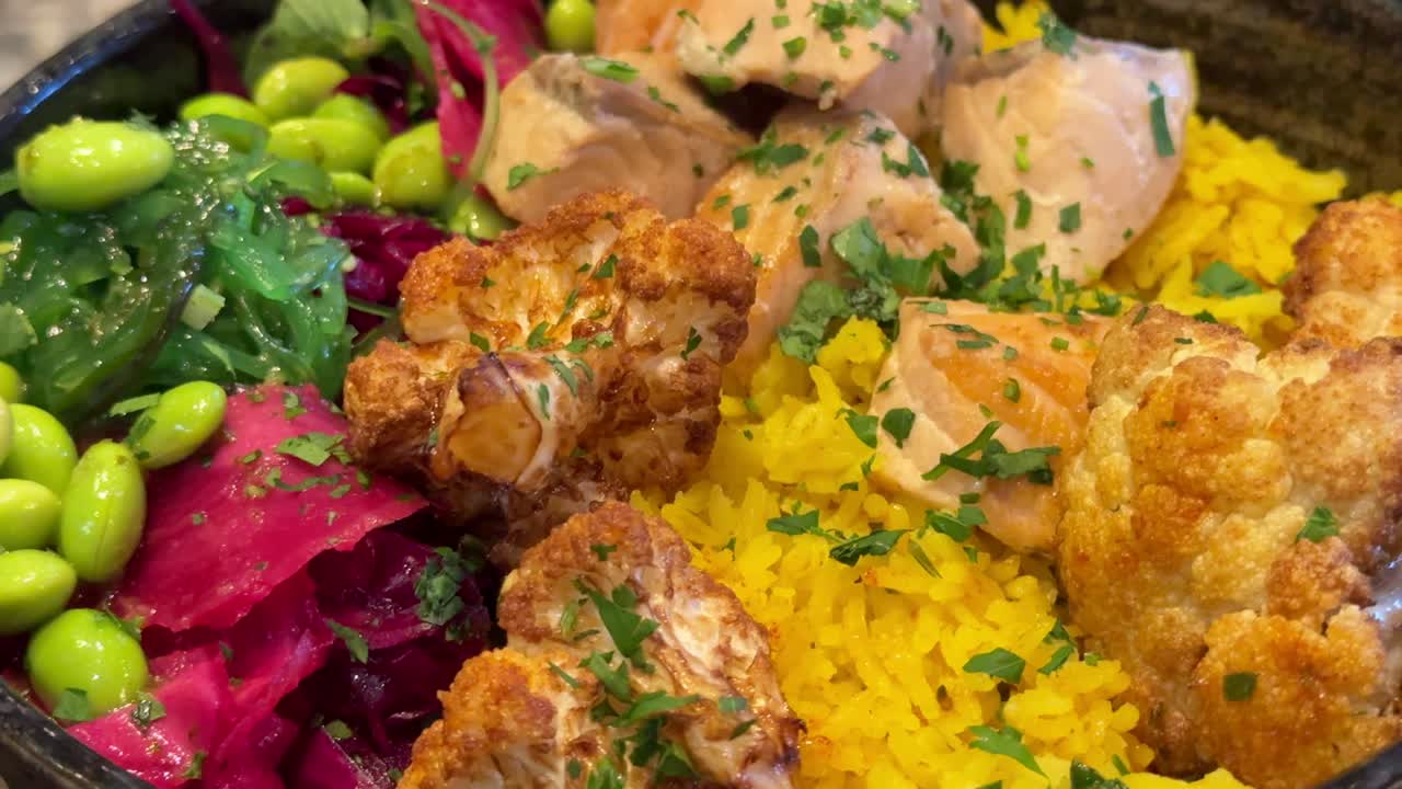 Healthy food bowl with fresh cooked salmon rice backed cauliflower, fresh edamame, red cabbage and brokkoli