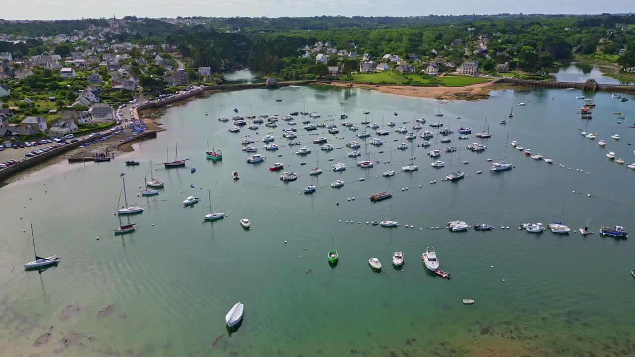 Smooth backward drone movement from the Ploumanac'h port with moored boats in a natural harbor of Perros-Guirec, Brittany, France.
