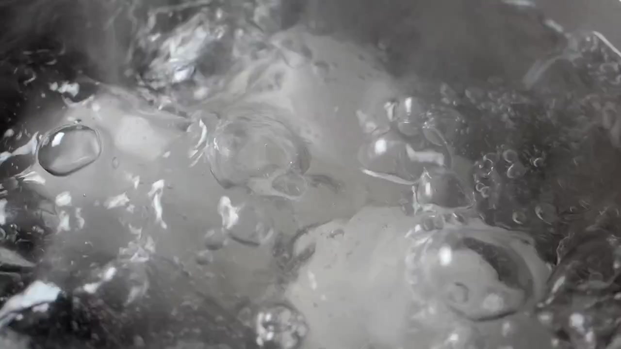 Acqua trasparente in rapida ebollizione con grosse bolle in una pentola