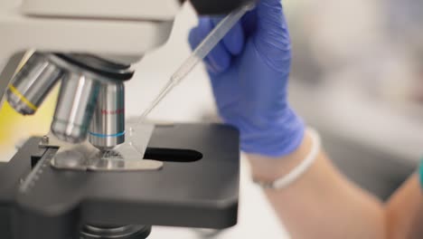 clínico en primer plano poniendo la gota en el portaobjetos del microscopio