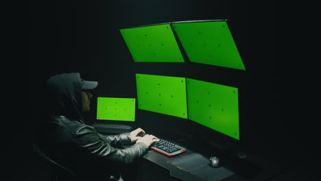 hacker working on multiple green screen computers