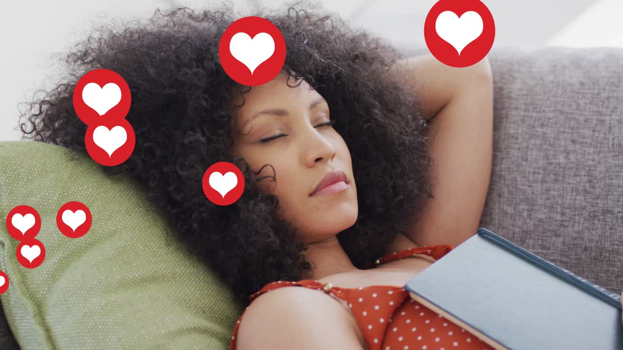 animación de los iconos del corazón de las redes sociales sobre una mujer biracial durmiendo en el sofá
