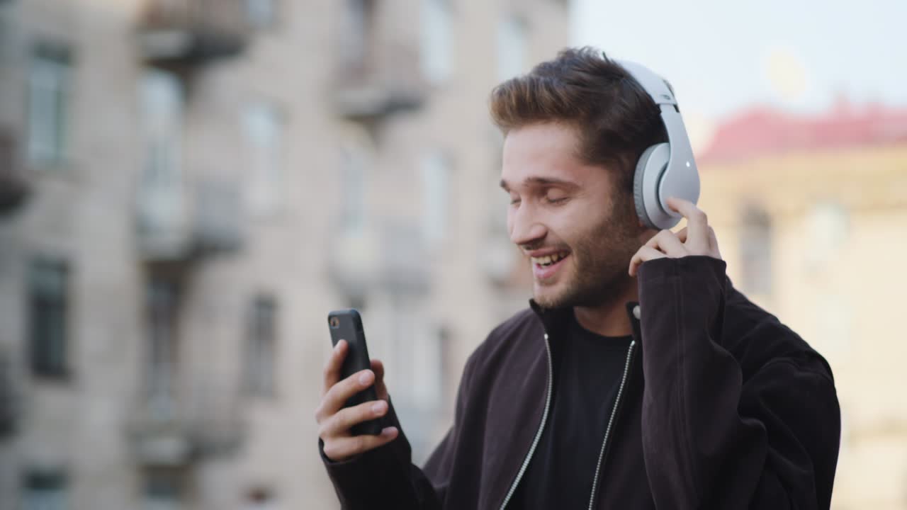 hombre feliz escuchando música auriculares afuera. hombre sonriente bailando en la calle de la ciudad
