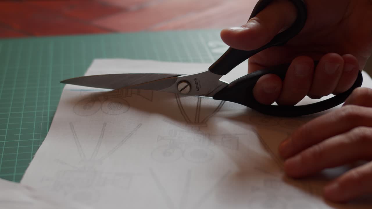 Cutting through fabric on a cutting board with scissors.