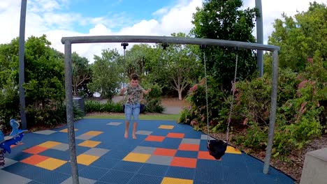 happy young boy swinging towards the camera while smiling and waving