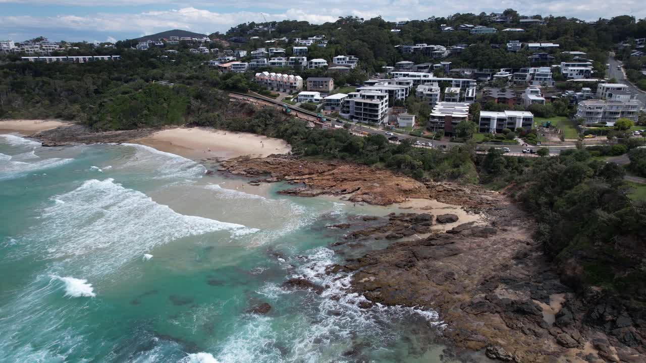Waves Coming To The Beach With Rocky Coastline And Beachfront Hotels In QLD, Australia. - aerial shot