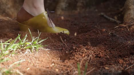 a woman wearing a yellow shoe splashing soil with her pams, white woman wearing yellow and brown fashionable shoes