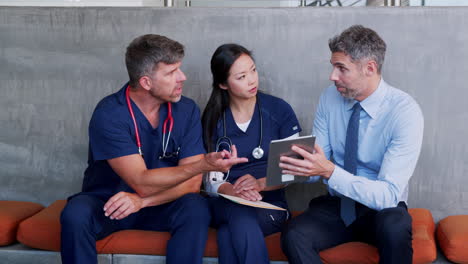 Tres-Médicos-Revisando-Información-En-Una-Tableta-En-El-Hospital.