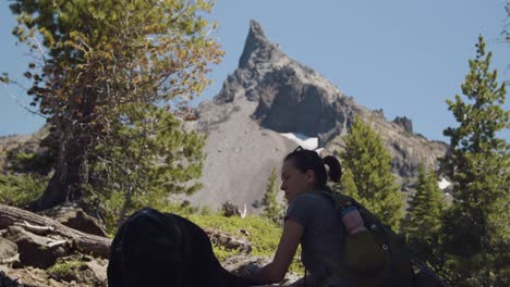 Girl-and-black-lab-taking-a-break-in-the-shade-during-mountain-hike