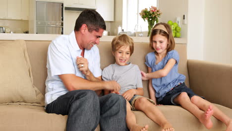 Father-and-daughter-tickling-son-in-the-couch