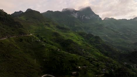 haang circuito curvo carretera a través de pasos de montaña y tierras de cultivo en terrazas al atardecer, toma panorámica de drone