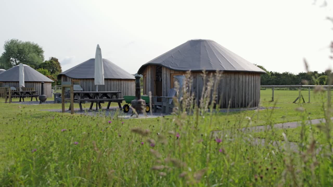 Wooden yurts and picnic area in lush countryside, summer glamping scene