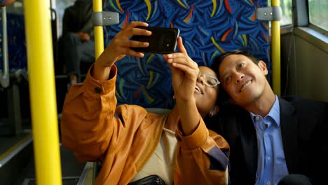 couple taking selfie on mobile phone while travelling in bus 4k