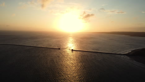 sunset over the ocean with a breakwater