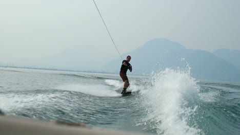 Vorderansicht-Eines-Kaukasischen-Jungen-Mannes,-Der-Tricks-Auf-Dem-Wakeboard-Im-Stadtfluss-Macht,-4k