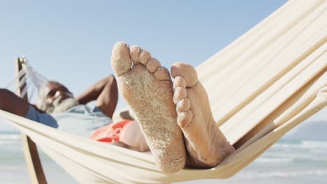 Glücklicher-älterer-Afroamerikanischer-Mann,-Der-In-Der-Hängematte-Am-Sonnigen-Strand-Liegt