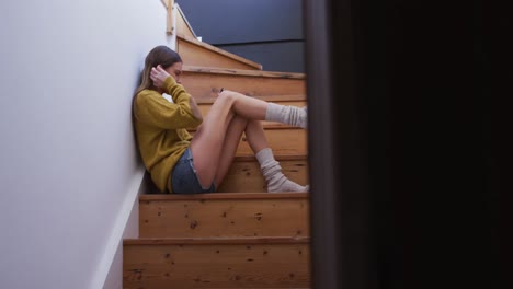 Woman-using-smartphone-while-sitting-on-stairs-at-home
