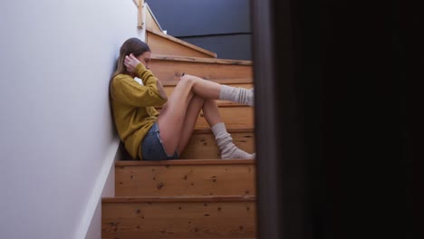 woman using smartphone while sitting on stairs at home