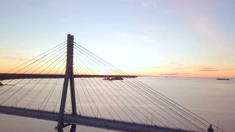 aerial, beautiful summer scenery in finland, cable stayed bridge lit up by orange sunset