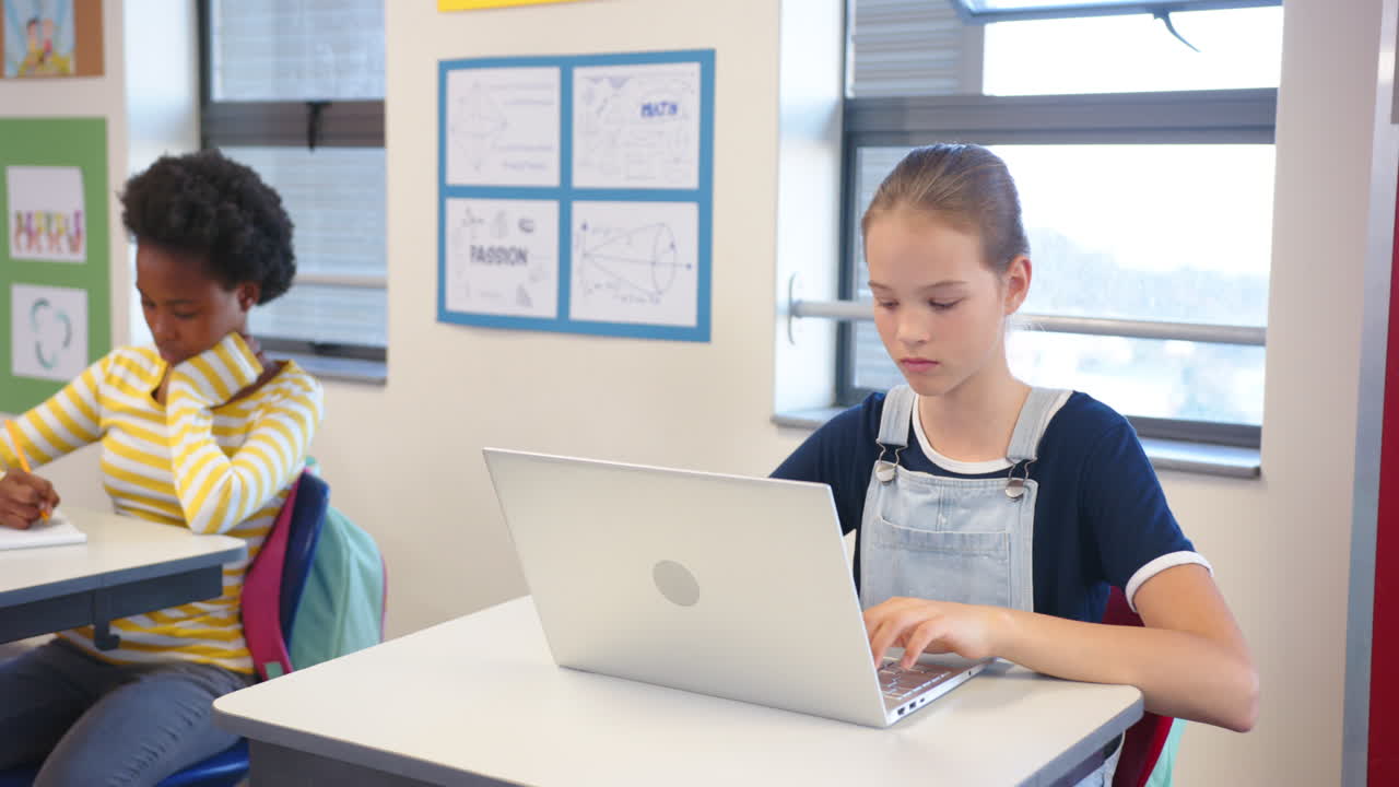 In school, girl using laptop and looking away, sitting at desk in classroom