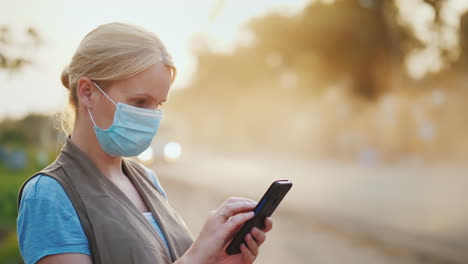 a woman in a mask to protect against dirty air uses a smartphone ecological problems