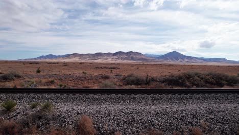 low drone shot over a railroad track with mountains and desert