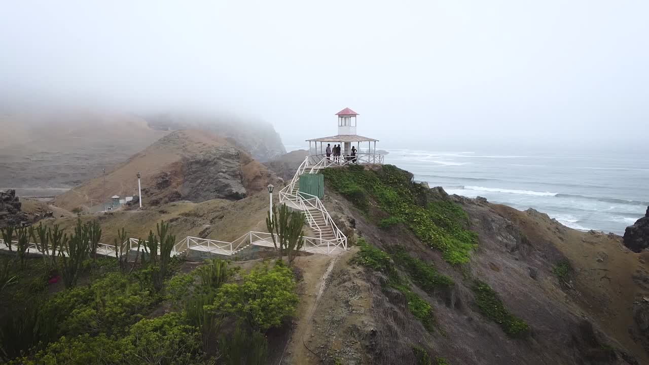 toma en órbita de personas reunidas en pérgula viendo vistas panorámicas al mar en clima brumoso, perú