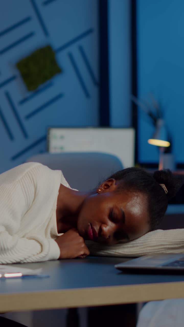 Vertical video Exhausted overload african business woman falling asleep on desk