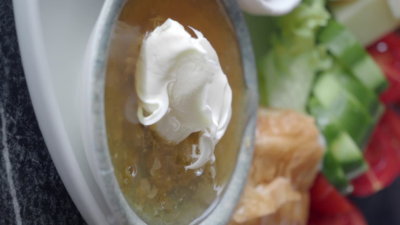 Close-up of a bowl of honey with cream, part of a breakfast spread