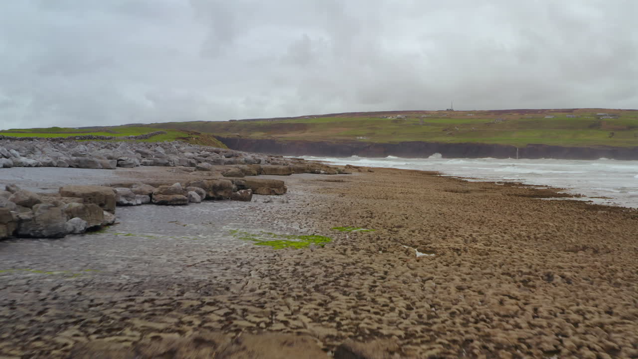 Aerial dolly follows rugged Doolin coast with imposing cliffs in background, Ireland