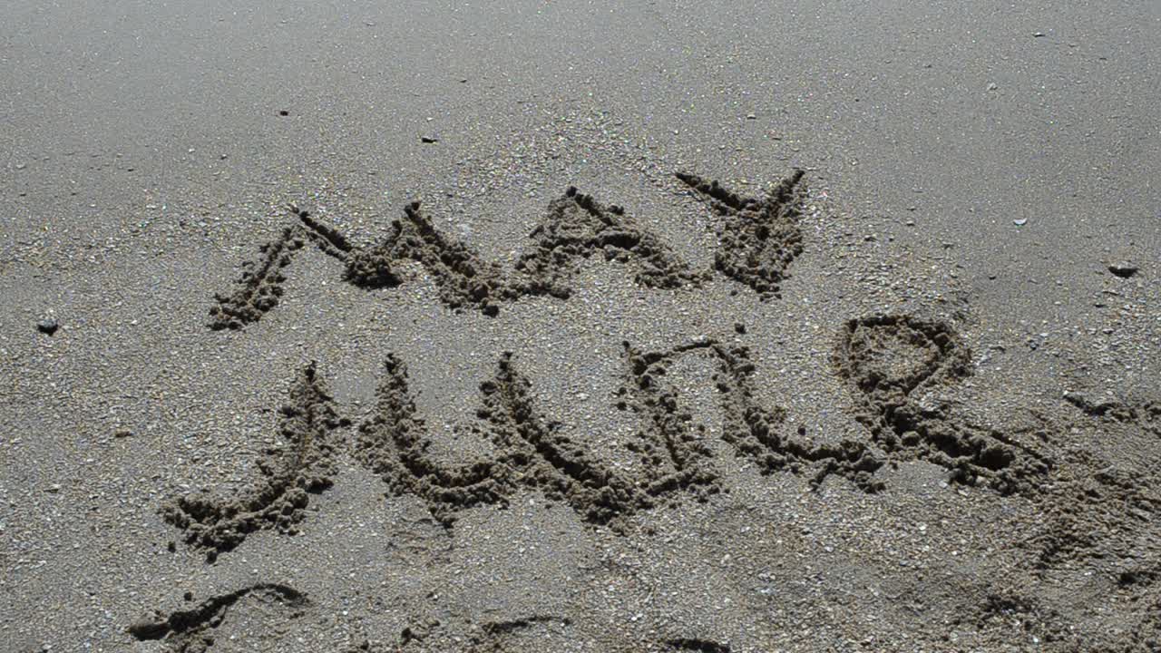 Iscrizione del nome del mese sulla sabbia, la spiaggia. Scatto sulla spiaggia.