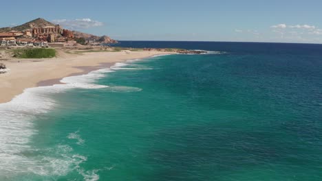 Aerial,-drone-shot,-overlooking-waves-and-turquoise-sea,-at-the-Sheraton-beach,-on-a-sunny-day,-in-Cabo-San-Lucas,-Baja-California-sur,-in-Mexico