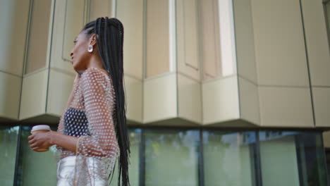 closeup trendy girl talking phone hold tea at city. dreadlocks woman walking