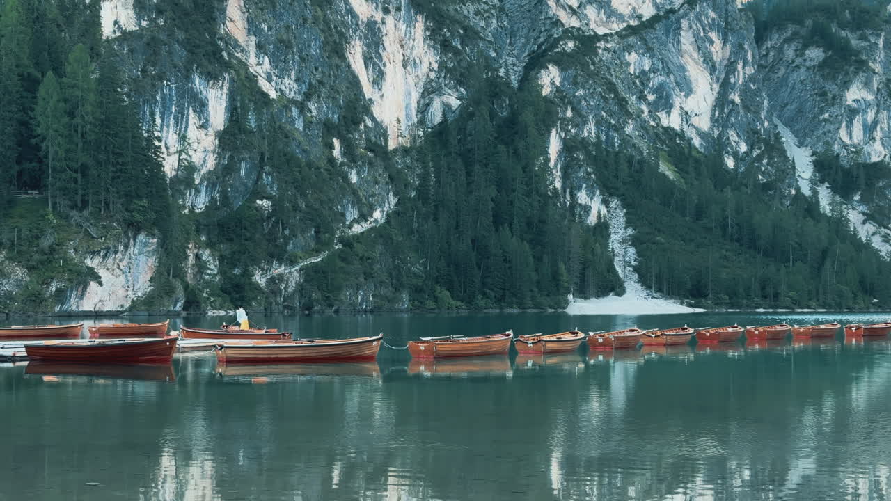 Tranquil scene of wooden boats resting on the calm waters of Lago di Braies, surrounded by the majestic Dolomites in Italy