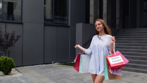 Pretty-girl-walking-from-centre-mall-with-shopping-bags,-happy-with-purchase-on-Black-Friday