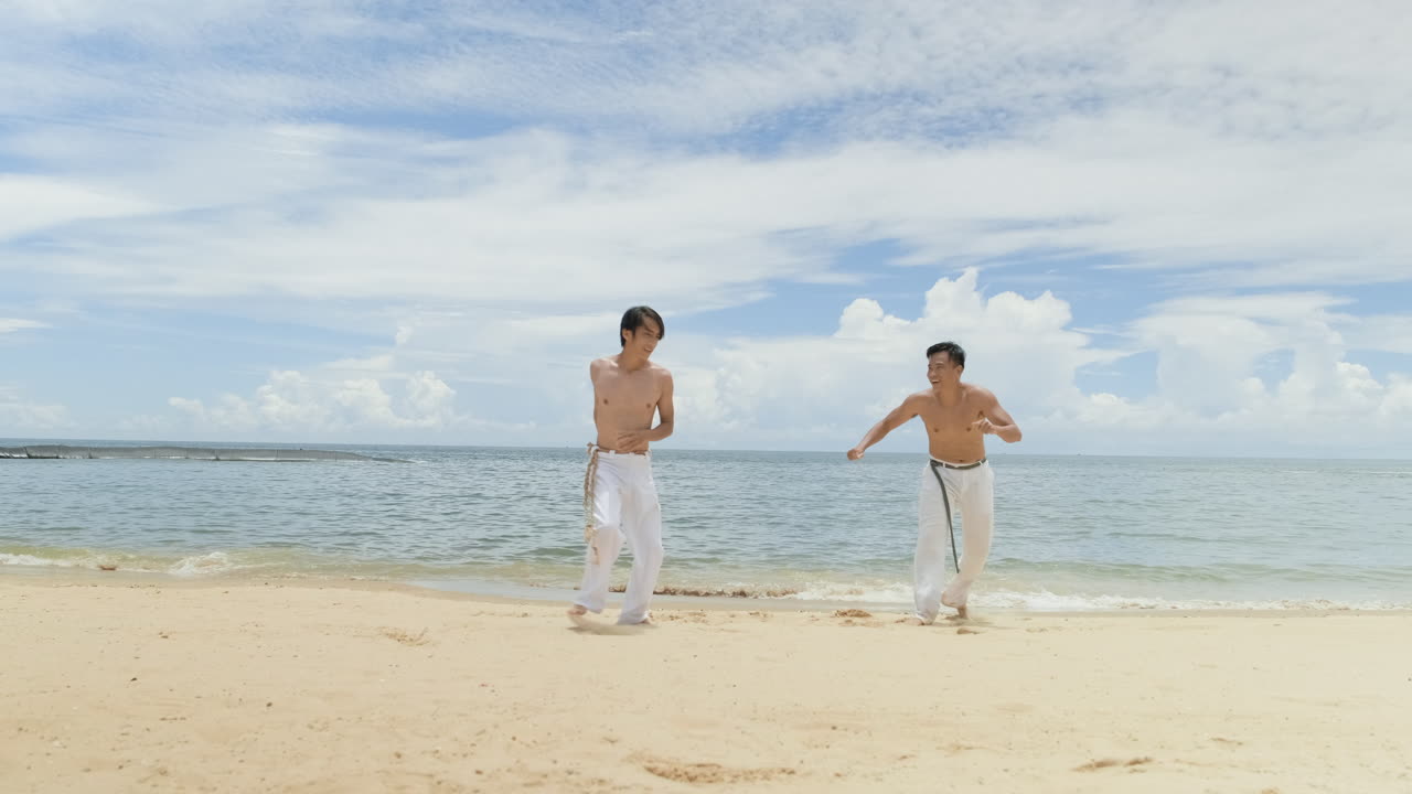 두 남자가 해변에서 카포에라를 춤추고 있다