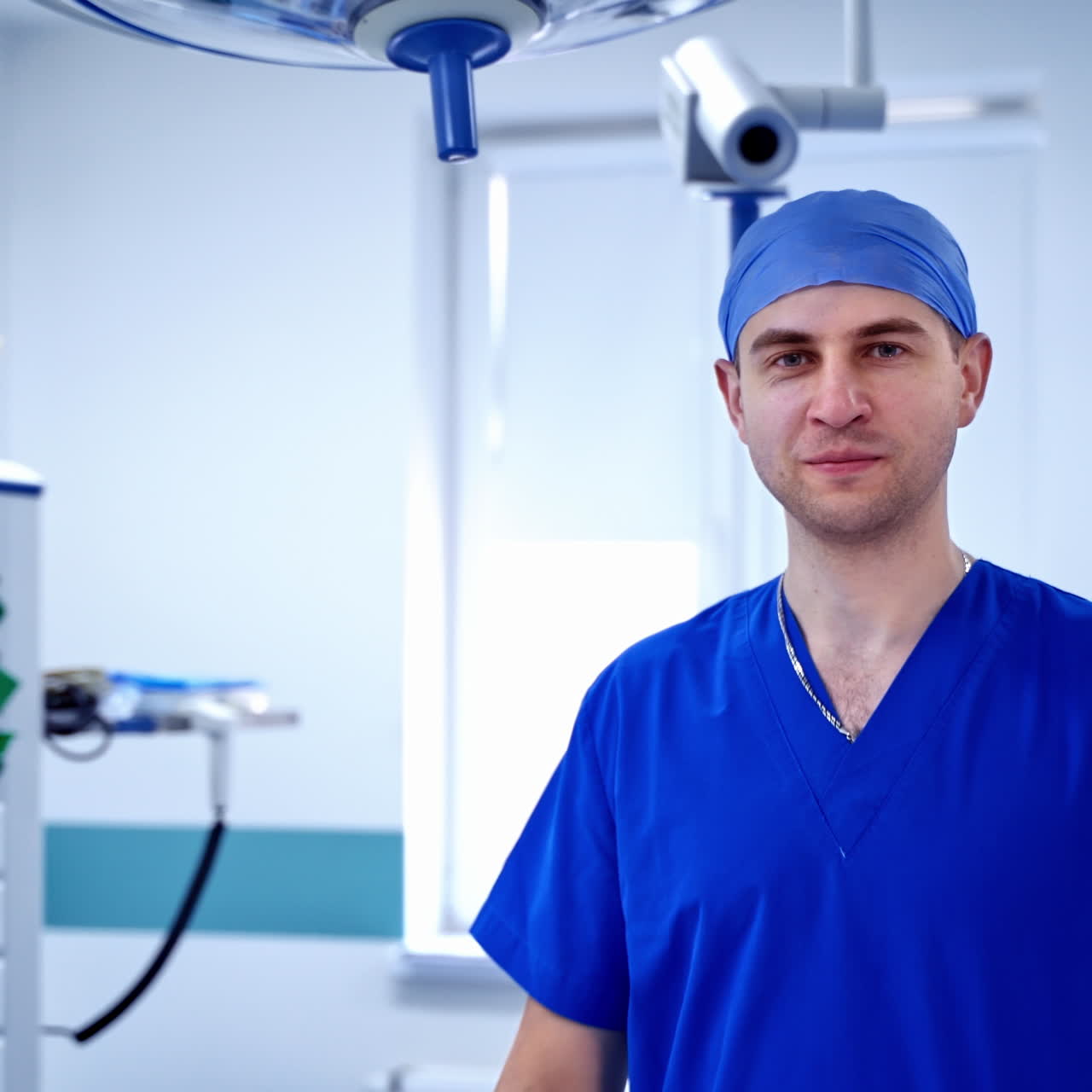 Portrait of a doctor on modern equipment background. Male surgeon in the operating room looking at camera. Health care.