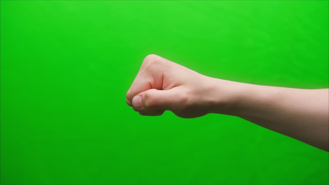 Close-up of a fist on a green background, shooting a hand gesture