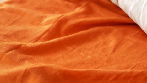 closeup of an orange bed sheet and pillow